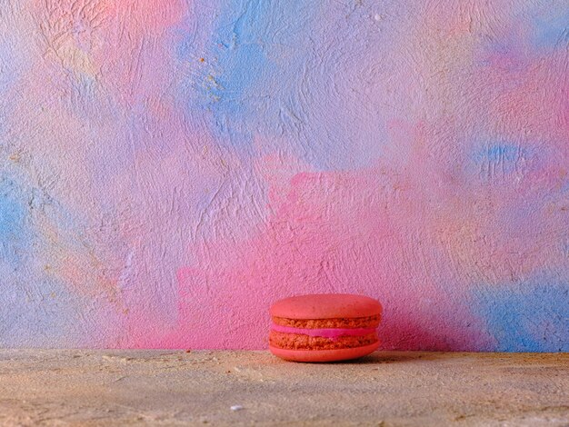 Photo macaron rouge sur un mur de couleur vive