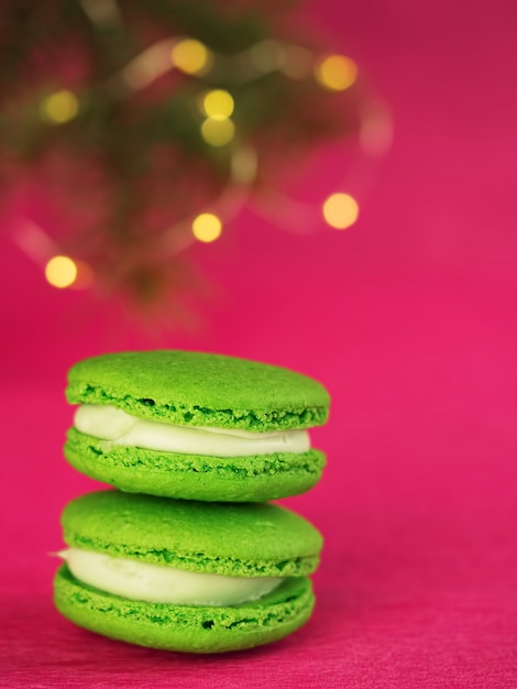 Macaron vert au fondant. Près d'une branche d'un arbre de Noël avec une guirlande.