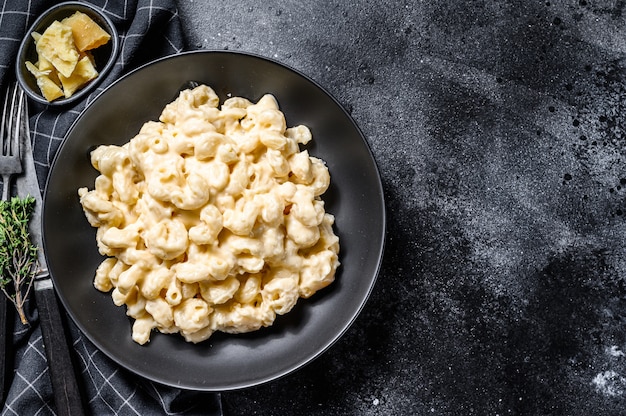 Macaroni au fromage, pâtes macaroni à la sauce au fromage. Fond noir. Vue de dessus. Espace copie