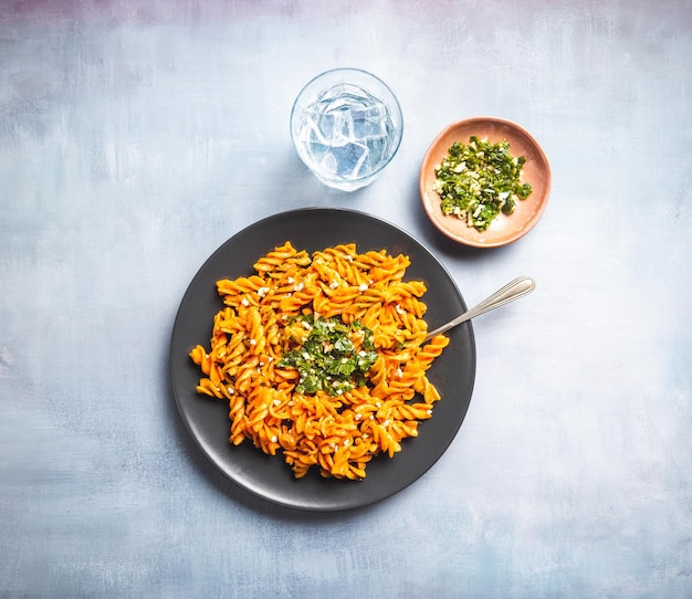 Macaroni aux pâtes frisées avec sauce tomate et gremolata dans une assiette sombre ronde sur une table