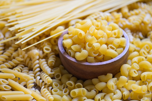 Macaroni cru sur bol en bois pâtes diverses sortes de pâtes non cuites spaghetti et nouilles sur fond concept culinaire de cuisine italienne Collection de différentes pâtes crues pour la cuisson des aliments