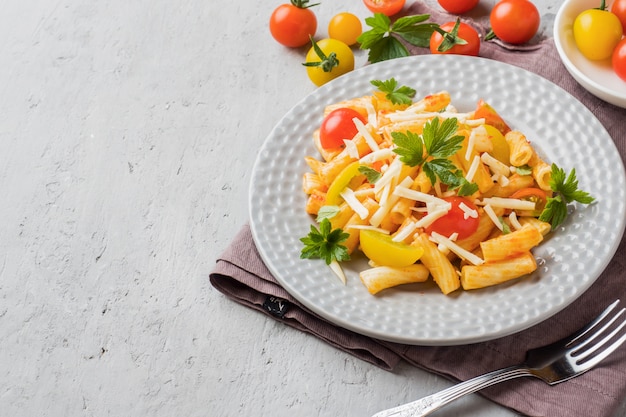 Macaroni, pâtes à la sauce tomate et fromage dans une assiette sur une table en bois.