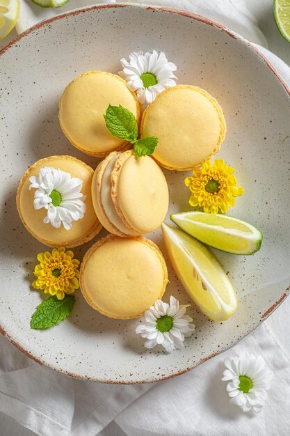 Macarons au citron savoureux et sucrés avec des fleurs de printemps sur assiette