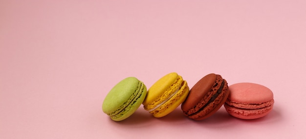 Macarons de biscuits français colorés sur fond rose, espace copie, photo horizontale