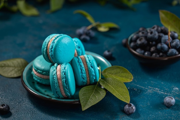 Macarons bleus et mûres sur un fond bleu foncé