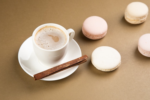 Macarons et café à la cannelle sur une surface grise.