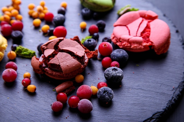 Macarons cassés avec des baies congelées sur fond gris.