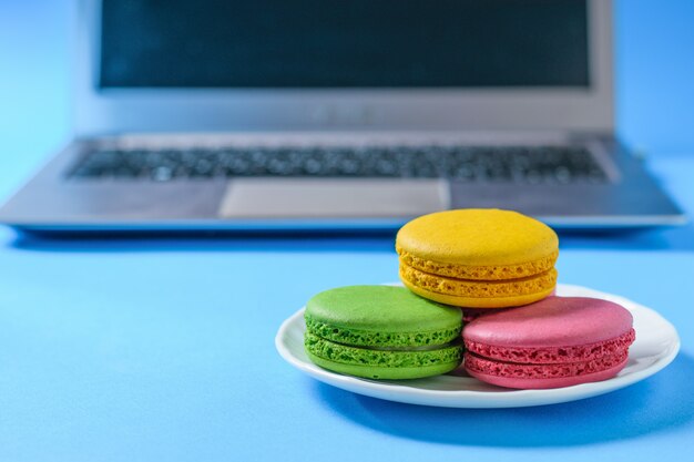 Macarons colorés dans une assiette blanche avec l'ordinateur.