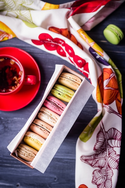 Macarons colorés dans une boîte cadeau et thé aux fruits