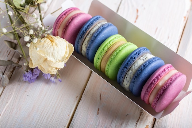 Macarons colorés dans une boîte sur un gros plan de table en bois clair