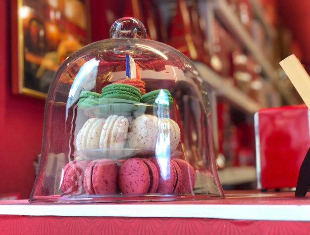 Macarons colorés dans une cloche de verre sur fond rouge