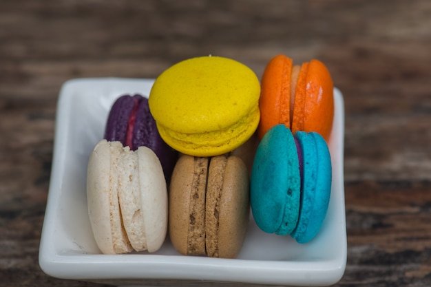 Macarons colorés dans un plat sur une table en bois