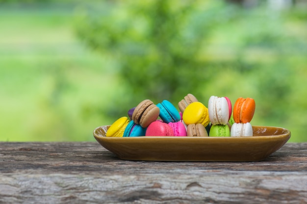 Macarons colorés dans un plat sur une table en bois