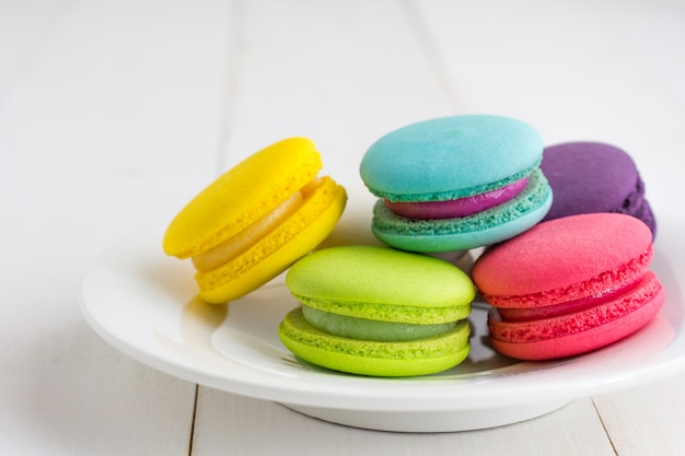 Macarons colorés sur un fond en bois blanc.