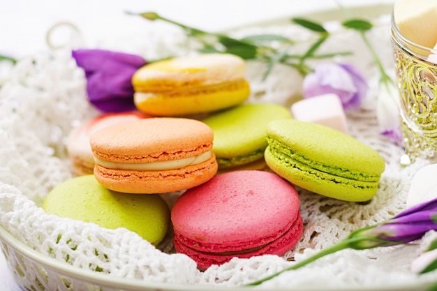 Macarons colorés et guimauves sur fond clair.