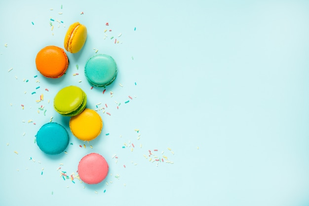 Macarons colorés et pépites de sucre disposés sur bleu