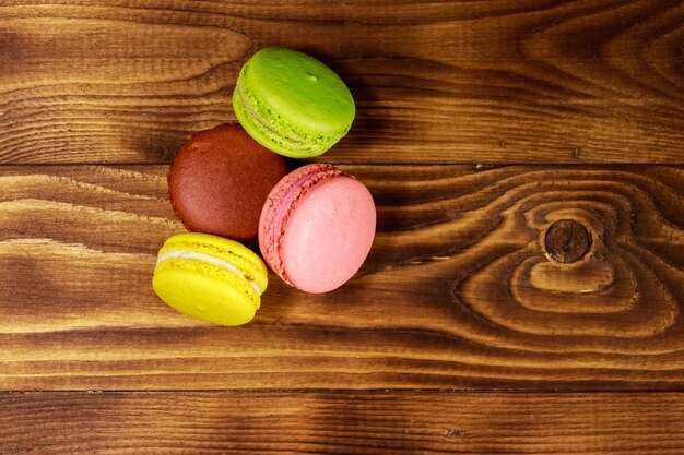 Macarons colorés savoureux sur table en bois. Vue de dessus, espace de copie