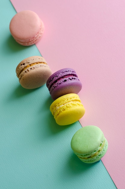 Macarons colorés sucrés sur pastel coloré.