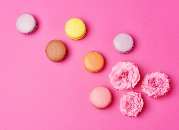 Macarons à la crème et un bouton de rose avec fond de pétales épars