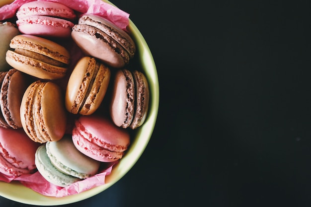 Photo macarons dans une assiette sur fond noir