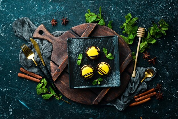 Macarons de desserts à la mangue jaune sur une plaque noire à la menthe Vue de dessus Style rustique