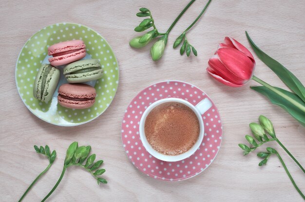 Macarons, expresso dans une tasse rose, freesias et tulipe rose, vue de dessus