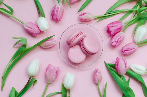 Macarons frais roses avec des tulipes sur rose