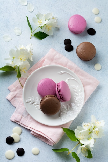 Macarons français au chocolat et cassis en assiette en céramique sur béton léger.