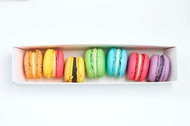 Photo macarons français doux et colorés dans une boîte blanche