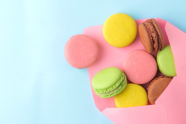 Macarons. gâteaux de macarons multicolores français dans une enveloppe. petit gâteau sucré français sur fond bleu clair. Dessert. Bonbons. vue de dessus.