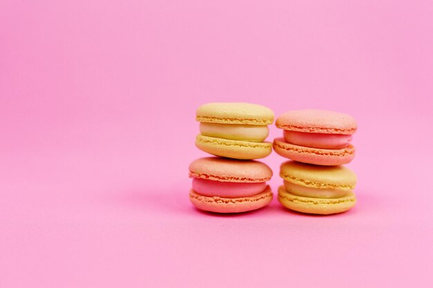 Macarons jaunes colorés dans des tons pastel sur fond rose