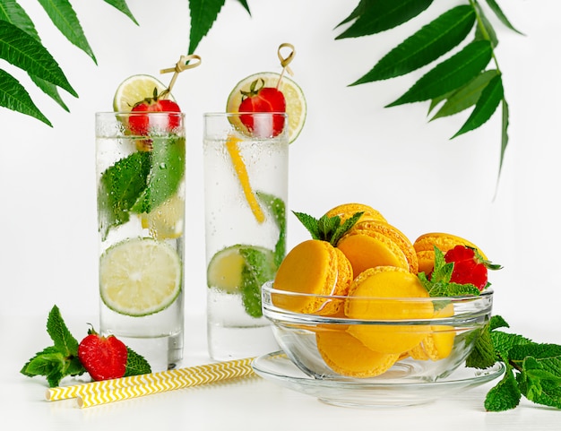 Macarons jaunes et limonade au citron vert, menthe et fraises sur blanc. Copier l'espace