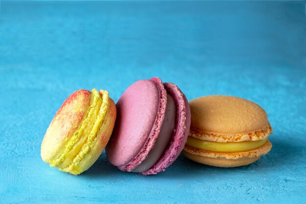 Les macarons jaunes et violets se trouvent sur une mise au point sélective de fond bleu