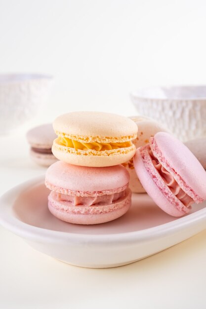 Macarons ou macarons français pastel colorés avec des tasses sur fond blanc