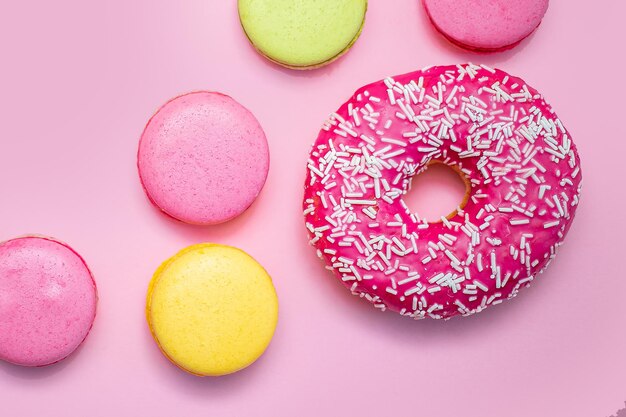 Macarons multicolores avec des beignets sucrés sur fond rose