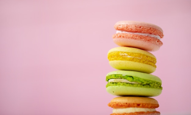 Macarons multicolores sur fond rose.