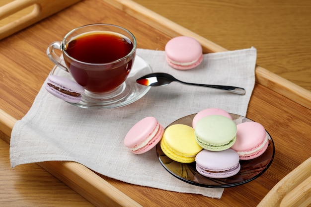 Macarons multicolores et une tasse de thé sur un plateau en bois Thé du matin et bonbons