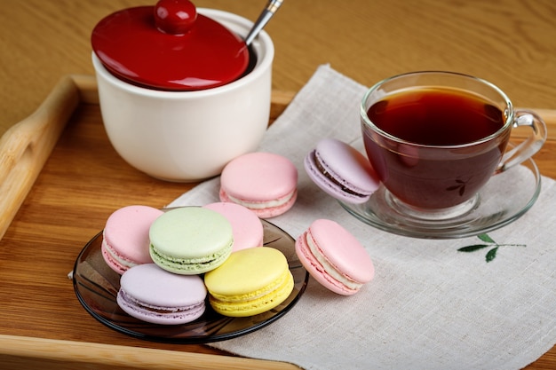 Macarons multicolores et une tasse de thé sur un plateau en bois