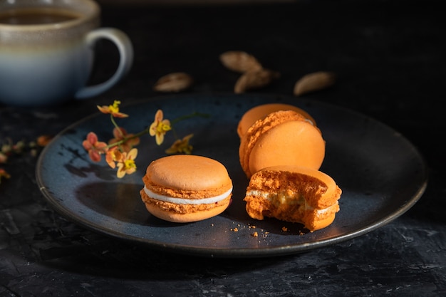 Macarons orange ou gâteaux macarons avec tasse de café