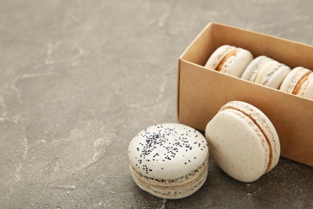 Macarons pastel en boîte sur fond gris Espace pour le texte