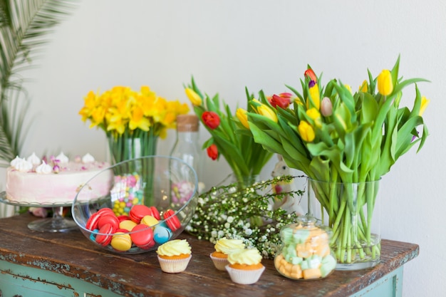 Macarons et petits gâteaux lumineux sur une table en bois. Lumière naturelle à l'intérieur avec une faible profondeur de champ