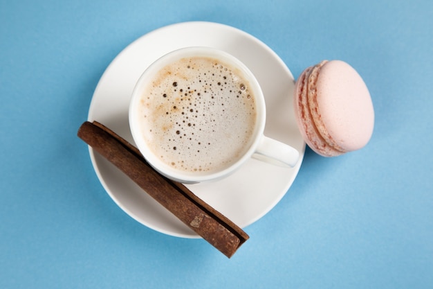 Macarons roses et café à la cannelle sur une surface orange