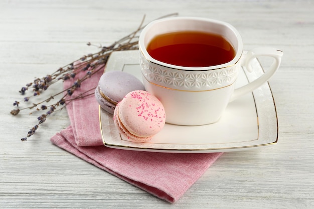 Macarons savoureux avec du thé sur la table en bois