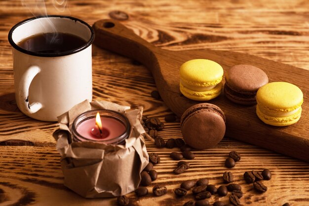 Macarons sucrés sur planche de bois avec une tasse de café et une bougie allumée Photo d'ambiance Contenu pour les réseaux sociaux