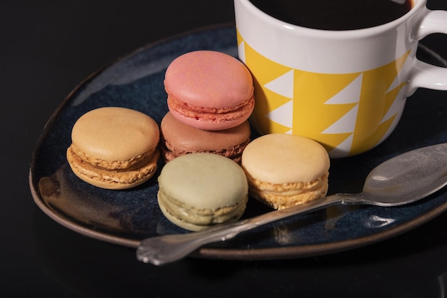 Macarons avec tasse de café sur fond noir