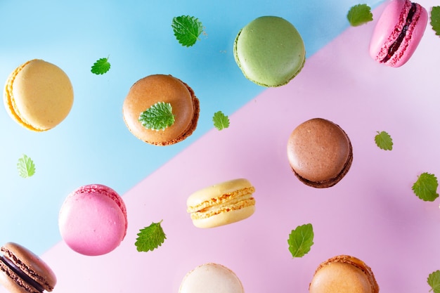 Macarons tombant avec des feuilles de menthe sur fond rose