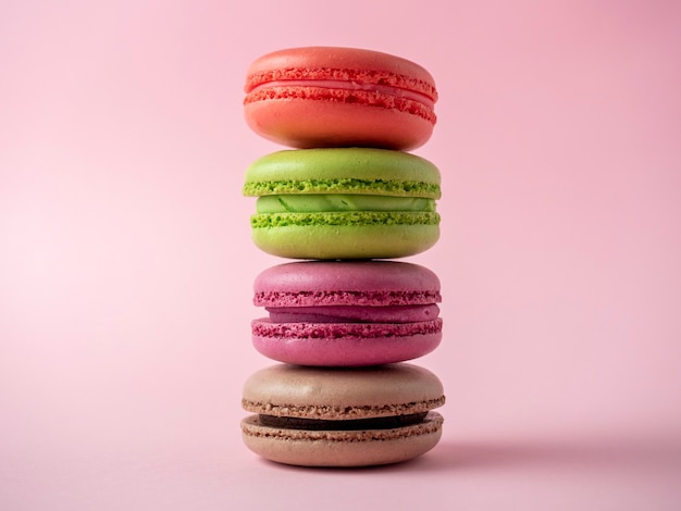 Les macarons traditionnels de différentes couleurs se dressent dans une pyramide sur fond rose. Article isolé, bonbons, confiseries. Vue de dessus, mise à plat