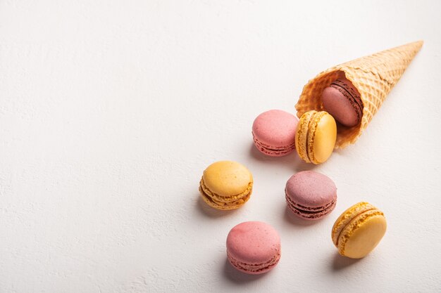 Macarons versés hors de cône de pâtisserie sur l'espace de vue de dessus de surface blanche