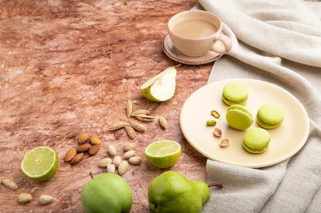 Macarons verts ou gâteaux macarons avec tasse de café sur fond de béton brun et textile en lin. Vue de côté,