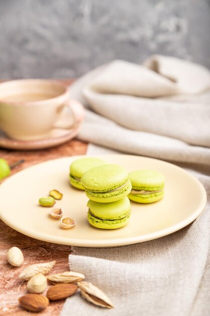 Macarons verts ou gâteaux de macarons avec une tasse de café sur un fond de béton marron Vue latérale mise au point sélective